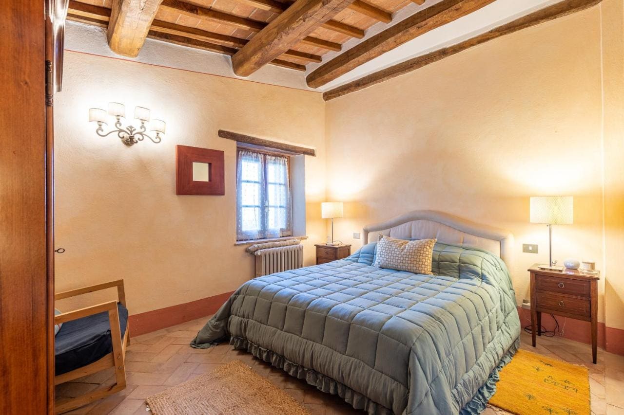 Camera da letto con travi a vista e pavimento in cotto